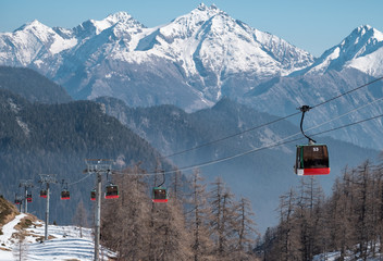 Row of cable cars against snowy italian mountains.