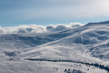 Fototapeta na wymiar Wonderful winter mountain landscape: Clouds lie on mountain snow-capped peaks Lago-Naki, The Main Caucasian Ridge, Russia