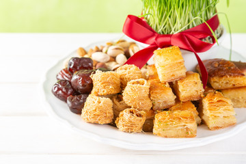 Nowruz holiday concept - grass, baklava sweets, nuts and seeds, copy space