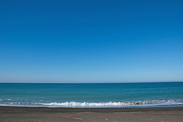 Fototapeta na wymiar 青い海と砂浜に打ち寄せる波