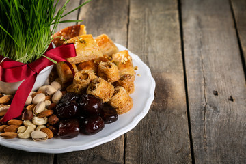 Nowruz holiday concept - grass, baklava sweets, nuts and seeds, copy space