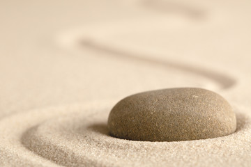 Fototapeta na wymiar Zen meditation stone with raked line in sand. Concept for harmony relaxation and purity.