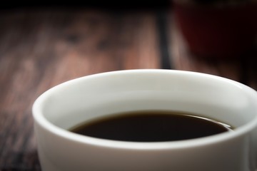 Black coffee in a cup on wooden table.