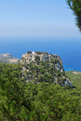 View of the mountain with the ruins of Monolitos Castle against the background of the sea and sky, the island of Rhodes, Greece