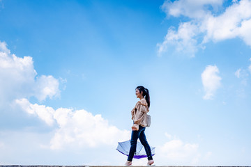 Beautiful Asia Woman holding umbrella with clear sky cloud background.