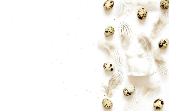 Easter composition with easter eggs, rabbit and feathers on white background, space for text - Image