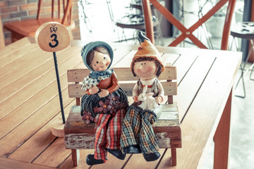Lovely vintage happy woman and boy doll in sitting position and wear costume country closeup on coffee wall blur background. Abstract of lovely family and warm love.
