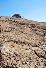 Close-up of a huge stone with a pyramid in the background against a blue sky, Cape Fourni, Rhodes Island, Greece