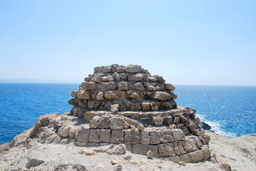 Close-up of a round pyramid made of stones against the blue sea and blue sky, Cape Fourni, Rhodes Island, Greece