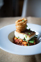 cod with stack on onion rings on bed of bean casserole 