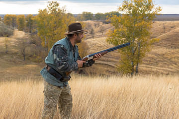 Hunter with a hat and a gun in search of prey in the steppe	