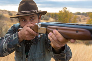 Hunter with a hat and a gun in search of prey in the steppe	