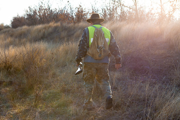 Hunter with a gun and a dog go on the first snow in the steppe, Hunting pheasant in a reflective vest	