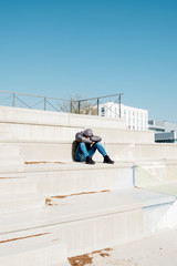 man curled up sitting on an outdoor stairway