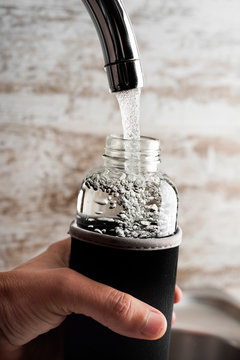 Man Filling A Reusable Water Bottle From A Tap