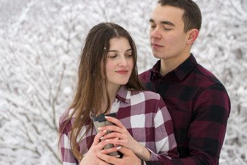 The guy and the girl have a rest in the winter woods. Husband and wife in the snow. Young couple walking in winter park