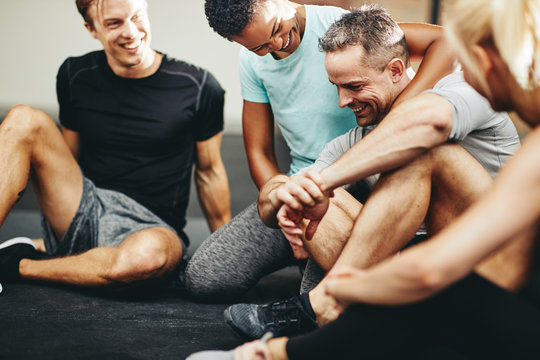 Laughing group of diverse friends sitting together in a gym