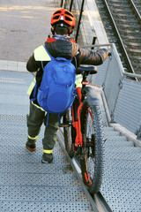 femme poussant son vélo sur une rampe d'escalier aménagée 