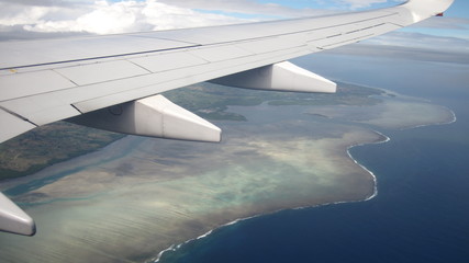 wing of an airplane flying over island