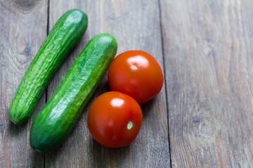 fresh cucumbers and tomatoes on wooden background