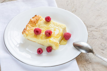 Cheese casserole with raspberries and honey on white plate on napkin on wooden cut. 
