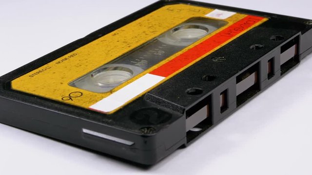 Vintage Yellow Audio Cassette Rotates on White Background