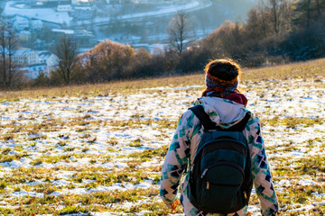 Junge Frau von hinten steht auf einem Feld im Sonnenschein