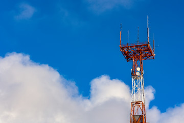 Tower connection with the mast and antennas against the blue sky with clouds. Transmission and reception of signals. 