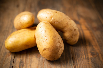Raw potato on wooden background.