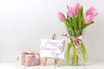 Bouquet of beautiful pink tulips flowers in a vase on a white wooden table. Spring. holidays. text happy women's day. free space