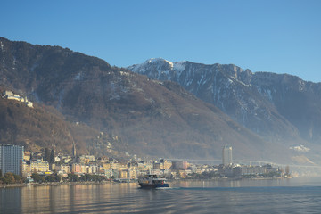 Montreux, Switzerland - 02 17, 2019: Ship cruising towards Montreux with mountains in the background.