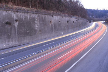 Car light trails on highway during twilight.
