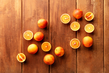 Organic blood oranges, whole and cut, shot from the top on a dark rustic background, forming a frame with a place for text