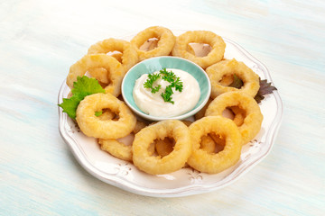 Obraz na płótnie Canvas A closeup photo of squid rings with mayonnaise and green leaves