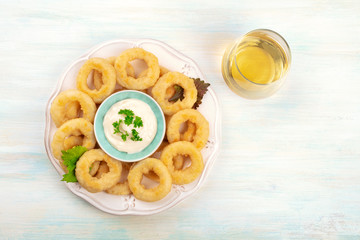 A photo of squid rings with lemon wedges and a glass of white wine, shot from above with a place for text