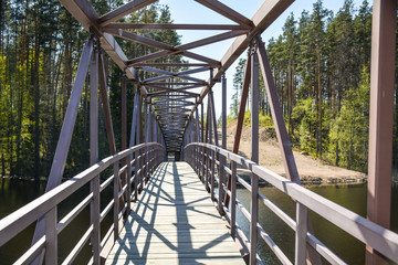 Fototapeta premium Openwork metal bridge to the church on the Vuoksa River, Russia