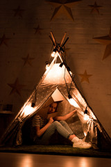 Preteen kid in cardboard helmet sitting in wigwam in dark room © LIGHTFIELD STUDIOS