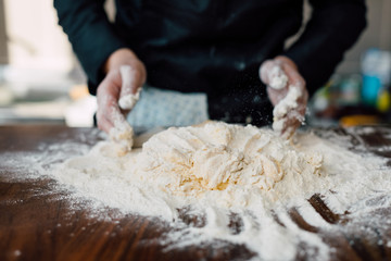 Female chef kneading dough in the kitchen
