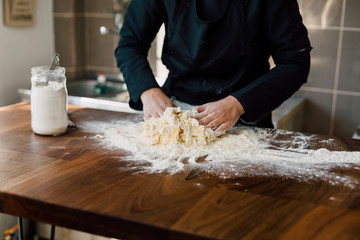 Female chef kneading dough in the kitchen