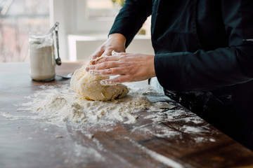Female chef kneading dough in the kitchen