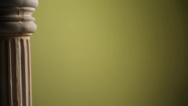 Single ancient greek column rotating slowly on color background, copy space text area