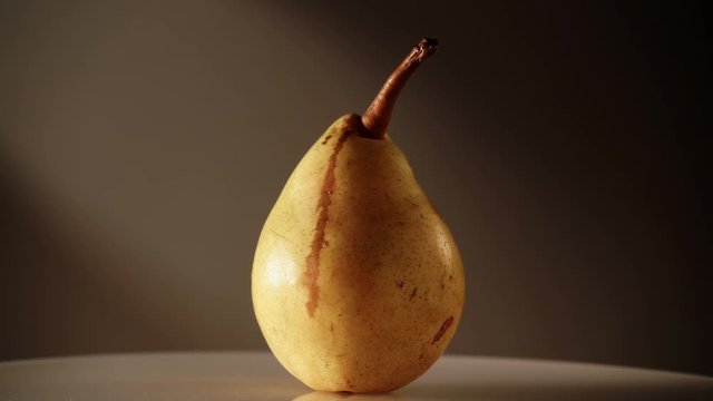 Yellow fresh ripe pear rotating slowly on dark. Healthy food organic nutrition