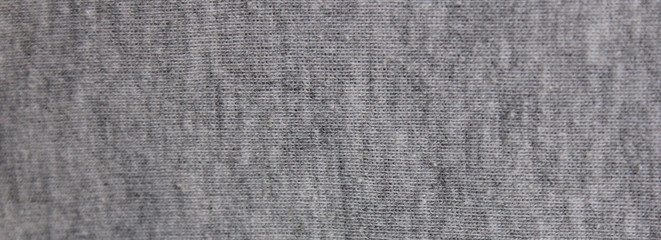 Gray fabric texture background of faded grey colored sweater. Cloth surface & material design for empty backdrop, modern fashion clothes pattern. Blank wide canvas and copy space template