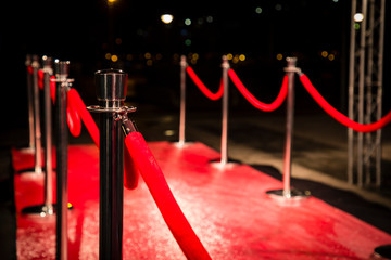 Red carpet with  barriers, velvet ropes and lights in the background