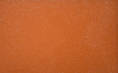 Orange pearlescent transparent background with metal splashes. Background. Texture. Close-up.