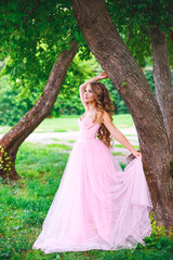 Fototapeta na wymiar Beautiful woman in pink dress posing in summer park