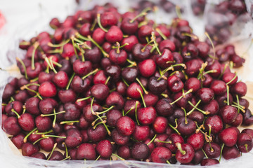 Fresh cherry in white plastic pakaging at street food market, front view.