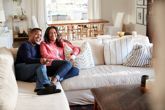 Middle Aged Couple Reclining On The Sofa In Their Living Room Watching TV, Selective Focus