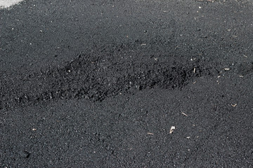 New asphalt surface with tire tracks