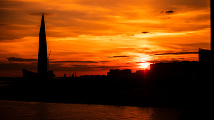 Fototapeta na wymiar Skyscraper in the rays of an apocalyptic sunset. Skyscraper during apocalypse